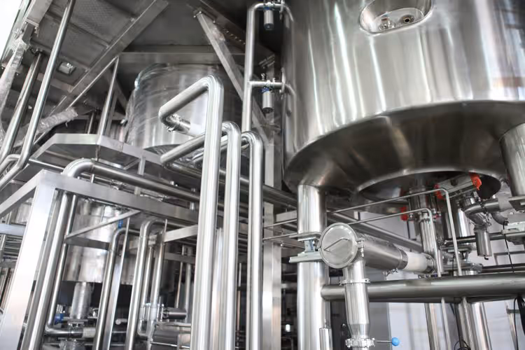 Stainless steel process vessels and pipework inside an industrial plant.